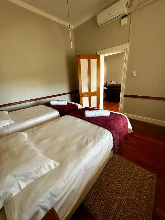 Twin beds with white linens and burgundy runner in spacious bedroom
