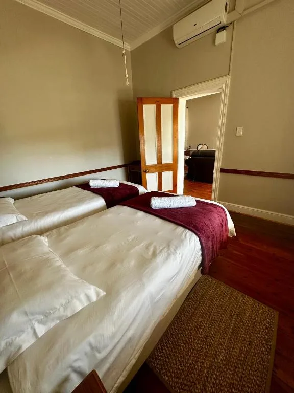 Spacious bedroom with two beds, burgundy runner, and wooden mirrored doors