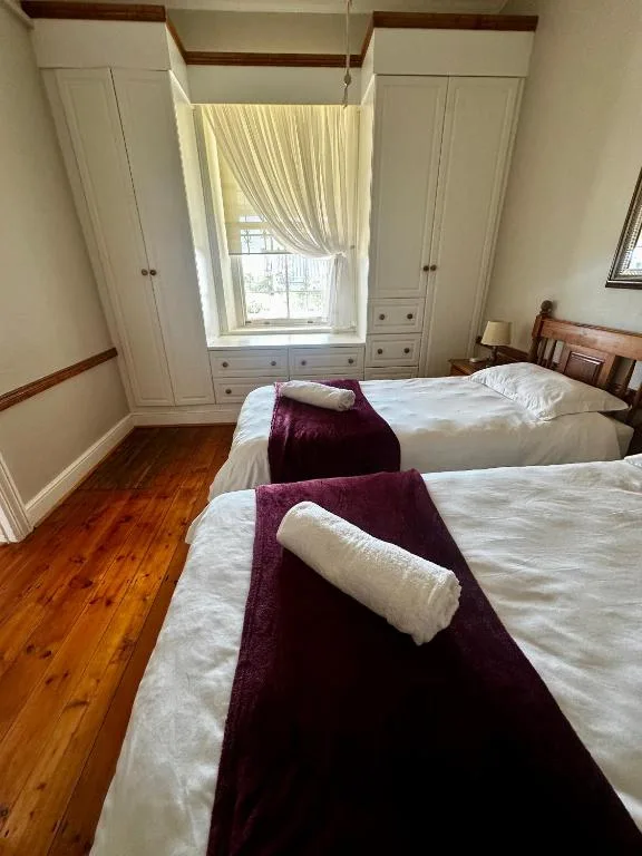 Bright bedroom with two beds, built-in wardrobes, and large window