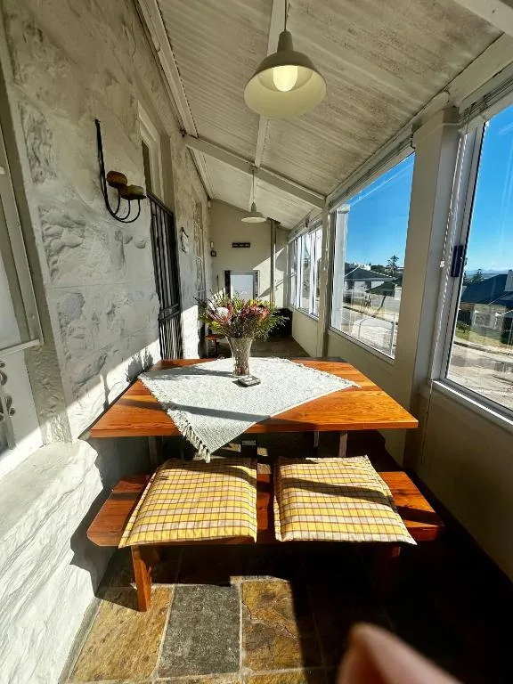 Covered outdoor dining area with wooden table and bench seating overlooking garden