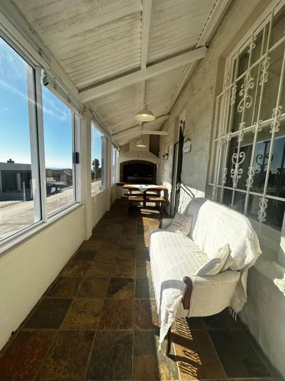 Covered porch with seating, windows overlooking gardens and coastal landscape