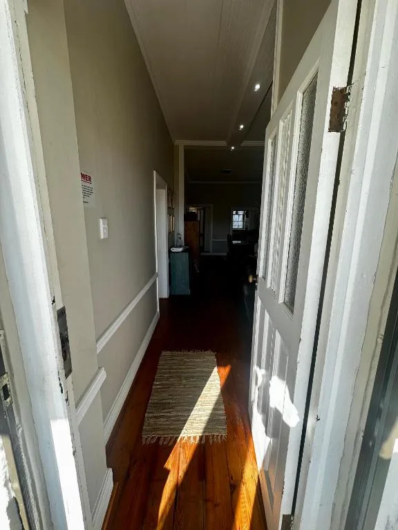 Hallway with wooden floors and white doors, natural light streaming in