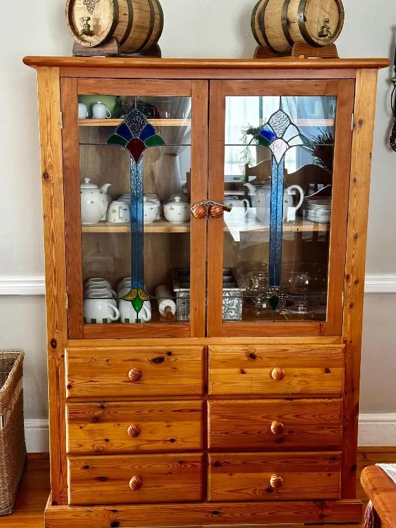 Wooden display cabinet with glassware, decorative barrels, stained glass