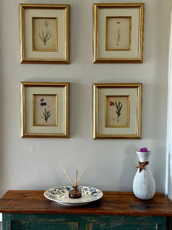 Four framed botanical prints and decorative items on wooden table