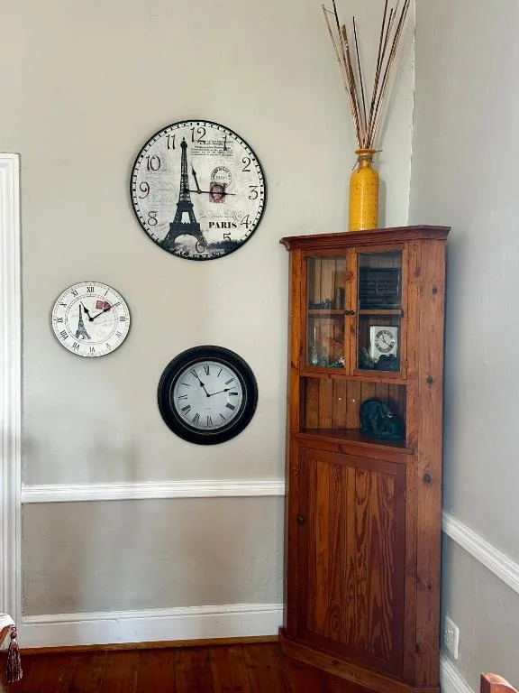 Decorative wall clocks and wooden cabinet with dried flowers in vase