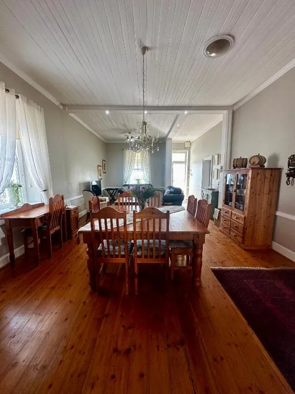 Spacious dining area with wooden table and chairs, pendant light fixture overhead