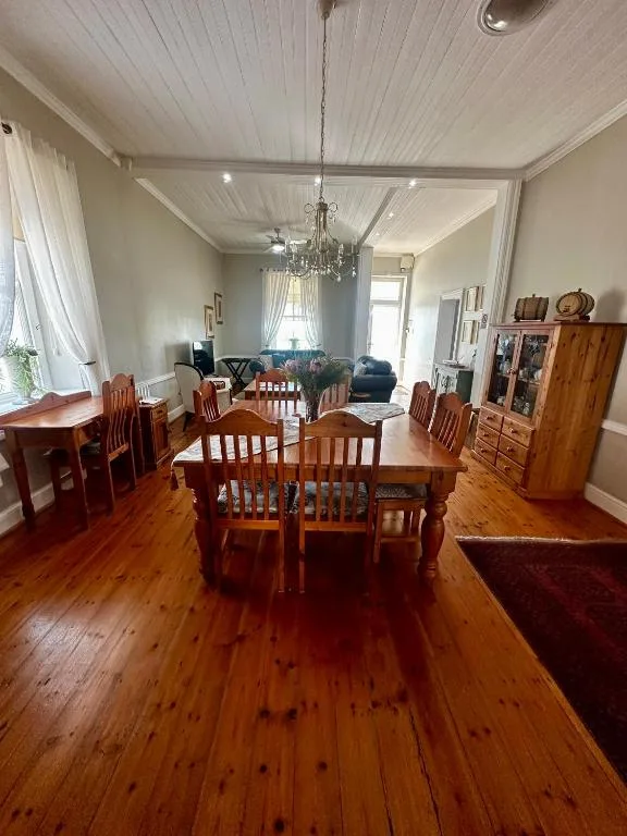 Spacious dining room with wooden table, chairs, and crystal chandelier overhead