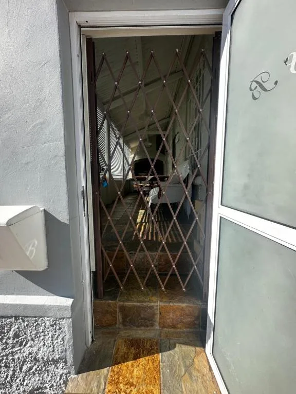 Security gate entrance to cottage with white walls and stone threshold