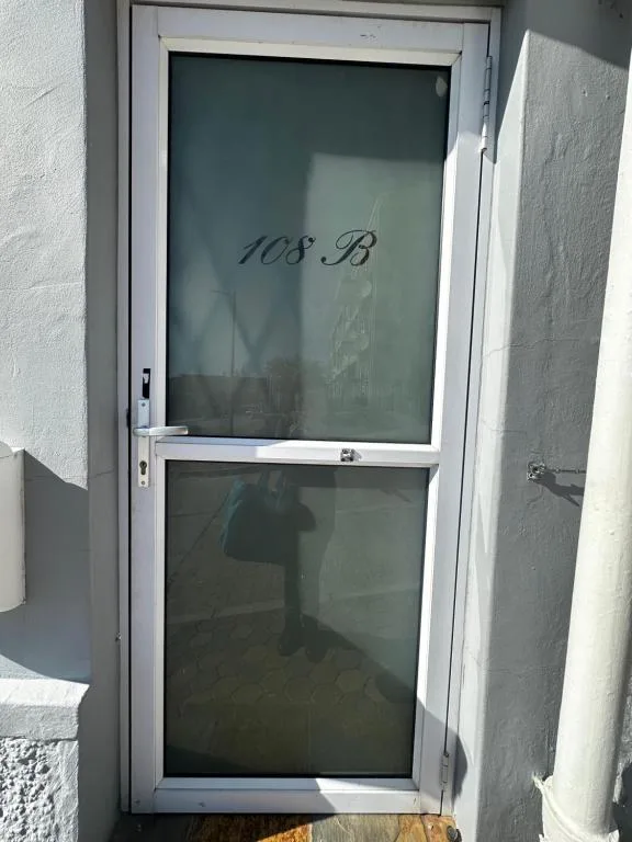 White-framed entrance door with unit number 108B marked on glass