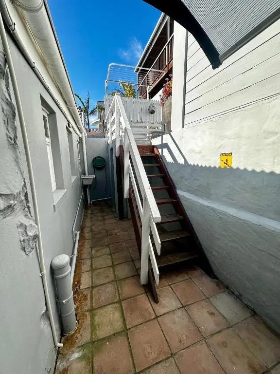 Narrow alleyway with white railing and stairs leading to upper deck