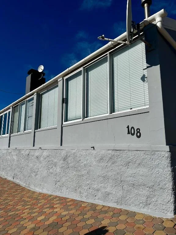 Modern white cottage exterior with numbered entrance and brick paving