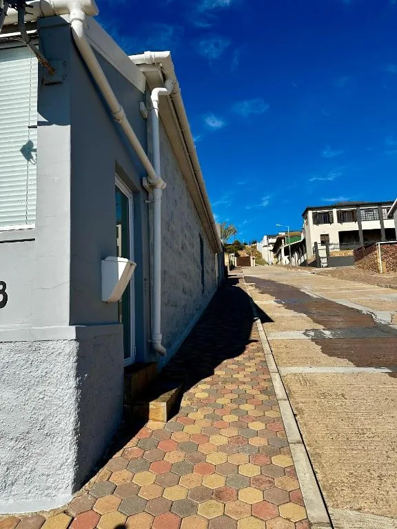 Modern cottage exterior with white walls and brick driveway under clear sky