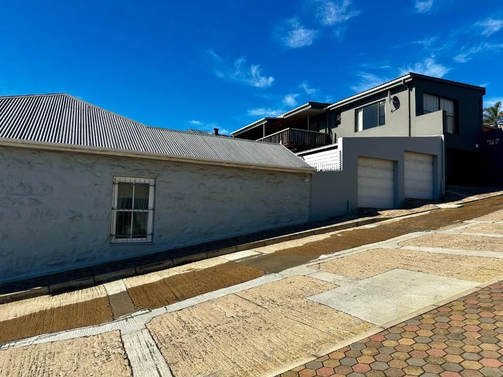 Modern residential building with white and dark facade, driveway, and clear blue sky
