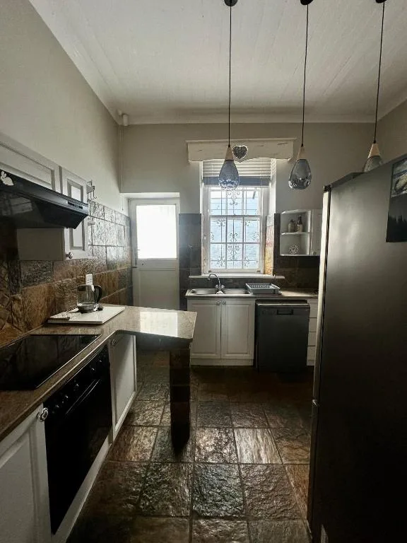 Modern kitchen with white cabinetry, black appliances, and pendant lighting