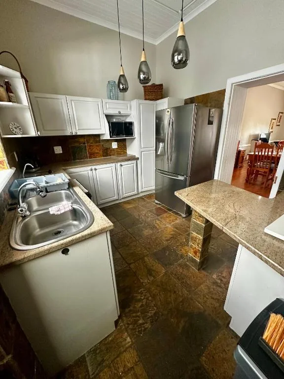 Modern kitchen with white cabinetry, stainless steel appliances, granite countertops, pendant lights