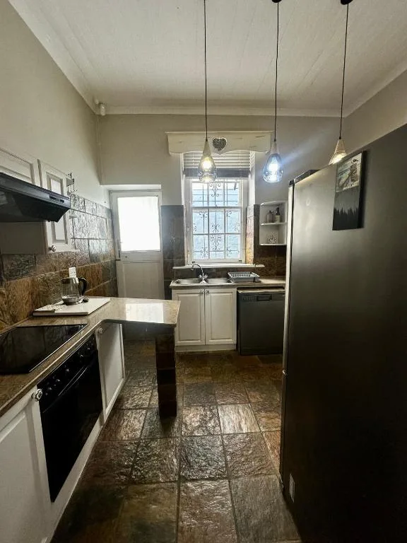 Modern kitchen with white cabinetry, black appliances, pendant lighting, and tile flooring