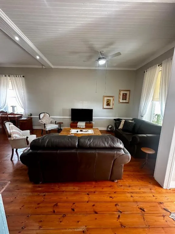 Spacious living room with black leather sofa and wooden floors
