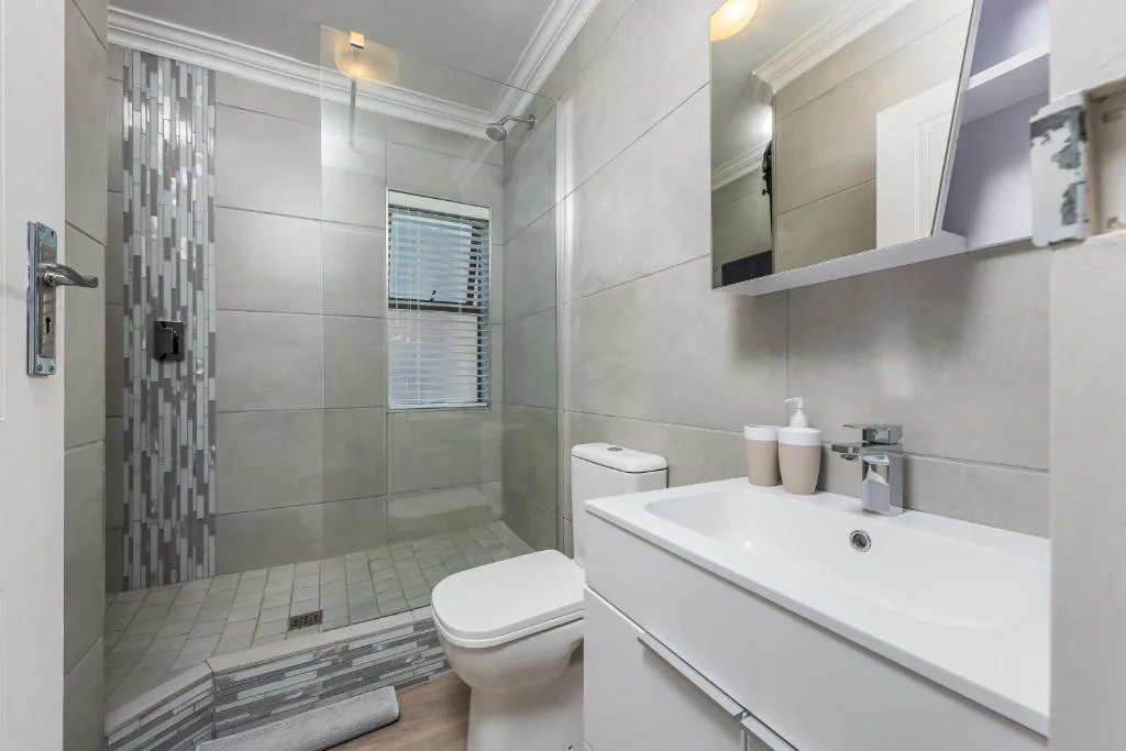 Modern bathroom with walk-in shower, white vanity, and tiled floors