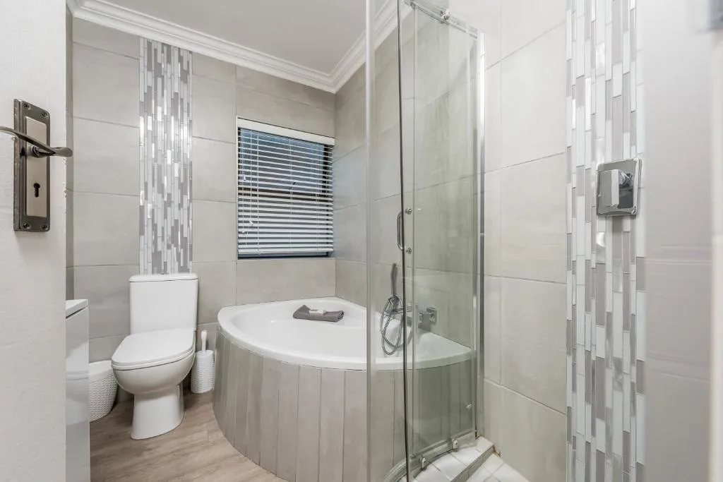Modern bathroom with curved soaking tub, walk-in shower, toilet and decorative tile accents
