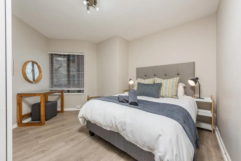 Spacious bedroom with queen bed, gray upholstered headboard, modern furnishings