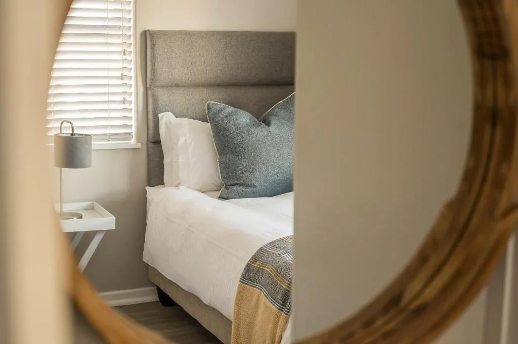 Modern bedroom with gray upholstered headboard and white bedding