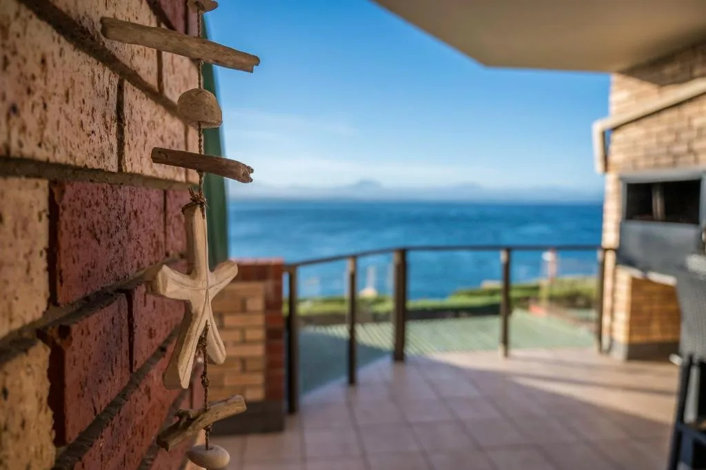 Coastal deck with ocean view, wooden railings, and starfish decorations