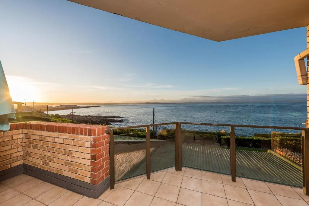 Spacious oceanfront deck with sea views and modern railings at sunset