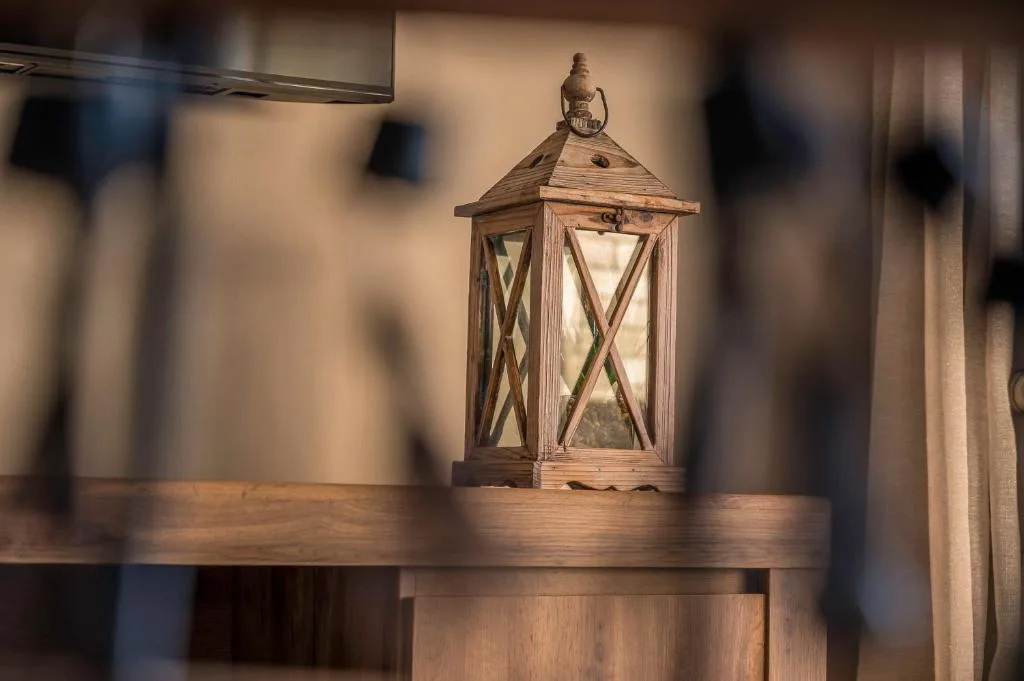Wooden lantern with cross-pattern glass panels on interior shelf