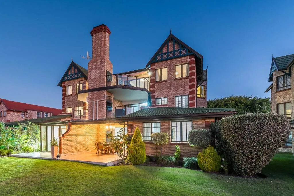 Victorian brick mansion with illuminated garden and manicured lawns at dusk