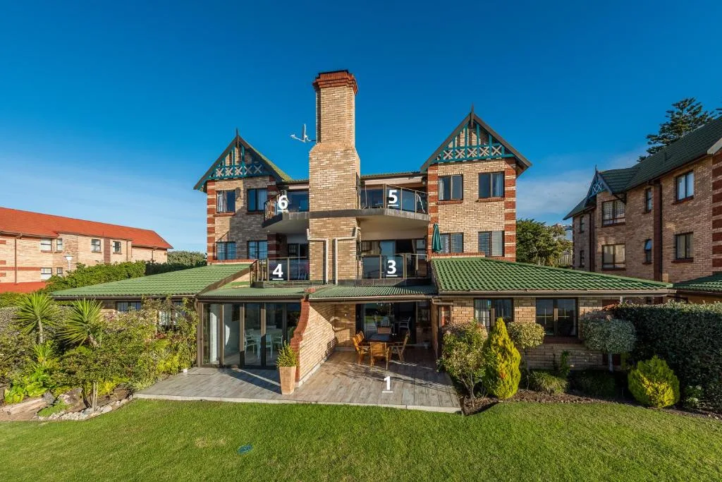 Victorian brick mansion with green roof and manicured garden lawn