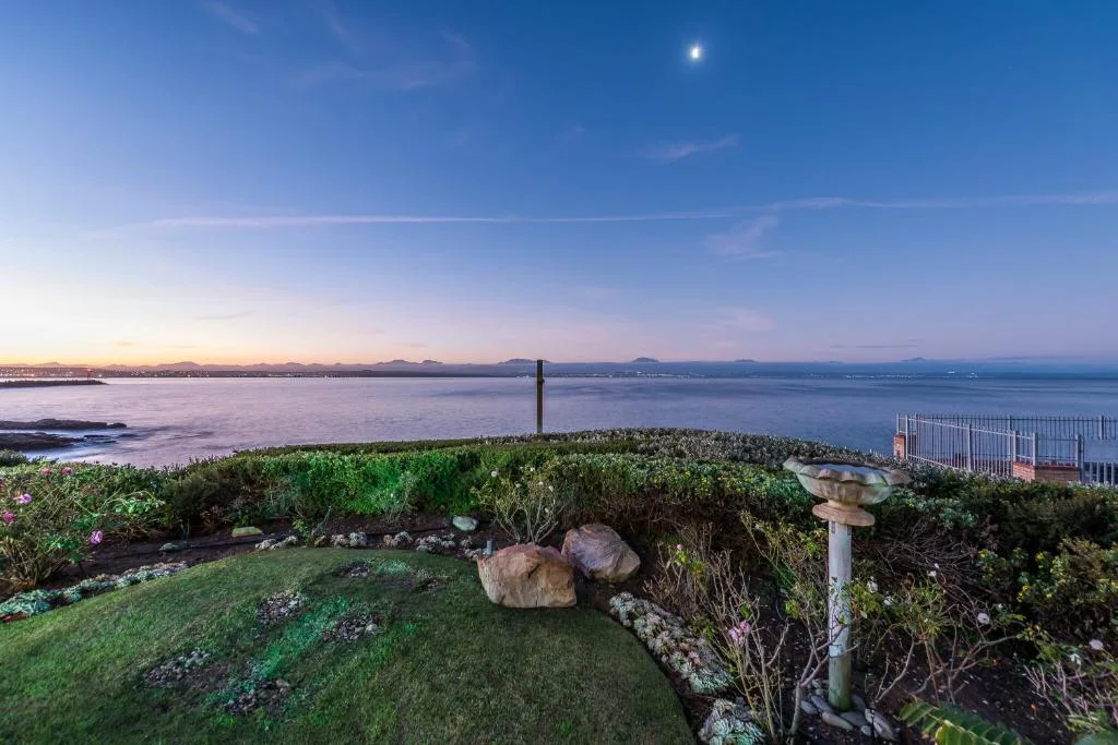 Scenic coastal vista overlooking calm bay with distant mountains and vegetation