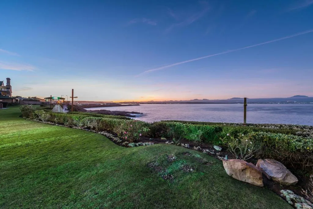 Waterfront sunset view with lagoon, mountains, and manicured garden grounds