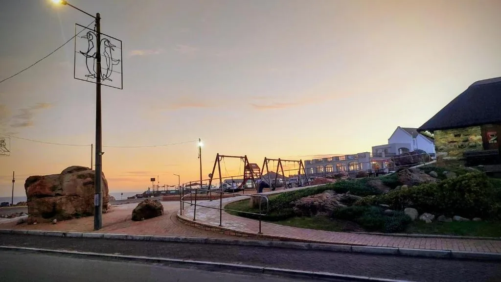 Sunset over Mossel Bay harbor with residential buildings and waterfront