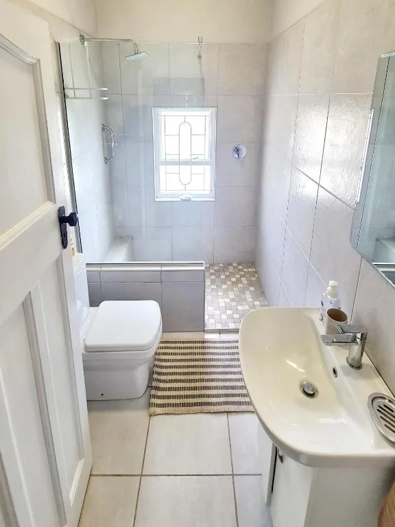 Modern bathroom with walk-in shower, toilet, and pedestal sink