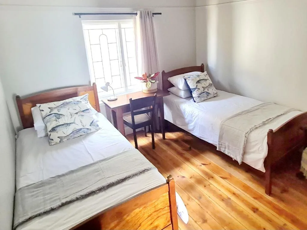 Twin bedroom with wooden beds, fish-patterned pillows, and bright natural light
