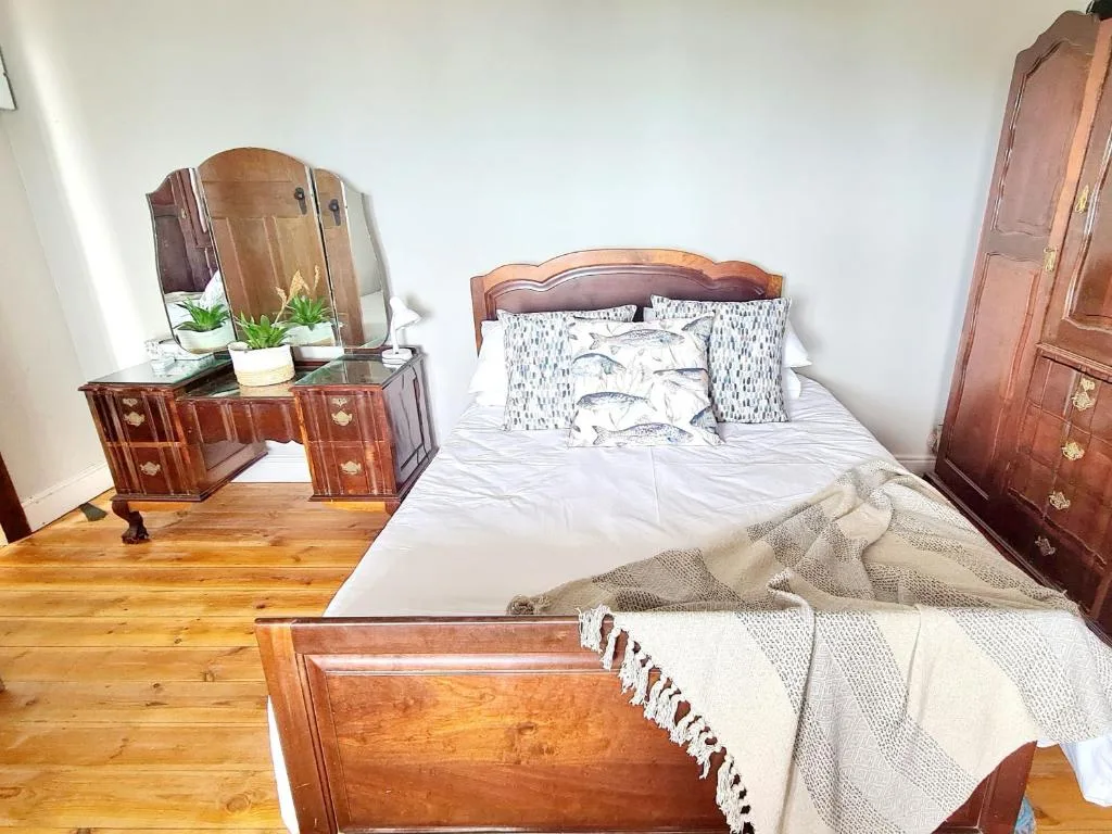Spacious bedroom with wooden bed frame and classic vanity dresser