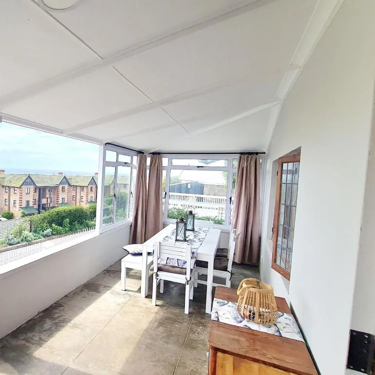 Covered outdoor deck with dining table overlooking coastal town buildings and garden views