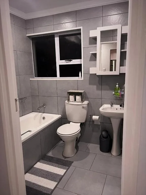 Modern bathroom with bathtub, toilet, sink, and window overlooking grounds