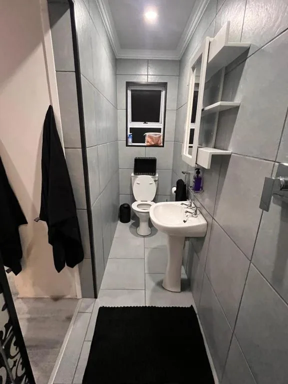 Modern bathroom with toilet, pedestal sink, and tiled walls
