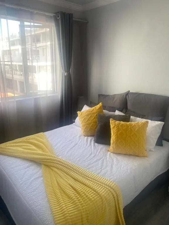 Bright bedroom with queen bed, yellow accents, and large windows