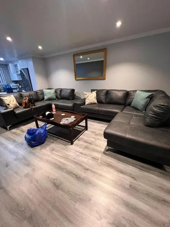 Spacious living room with black leather sectional sofa and wooden coffee table
