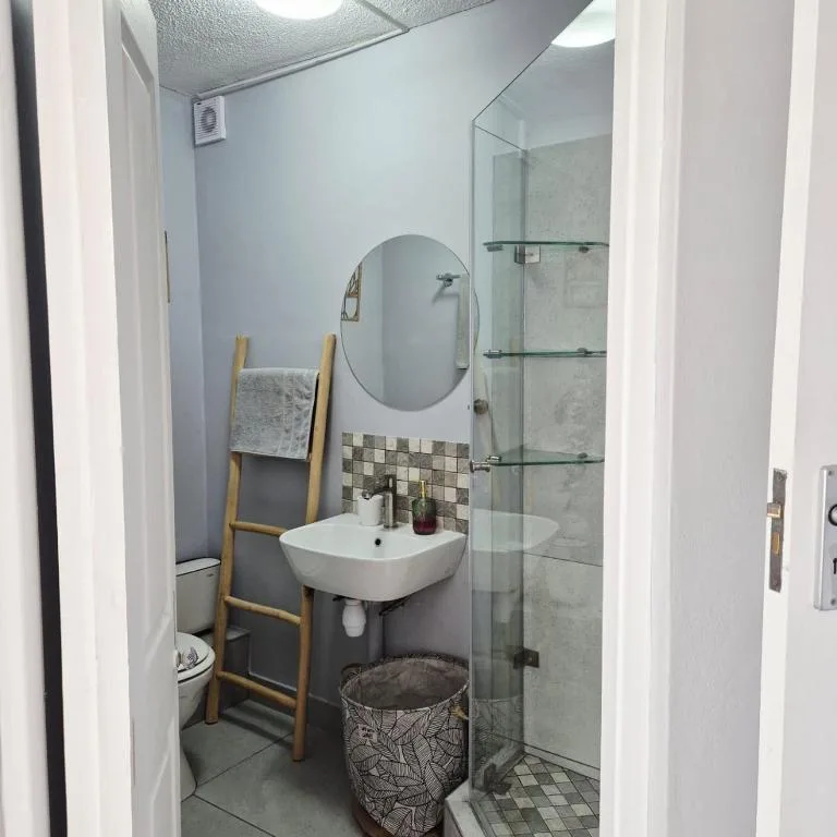 Modern bathroom with walk-in shower, round mirror, and white sink vanity