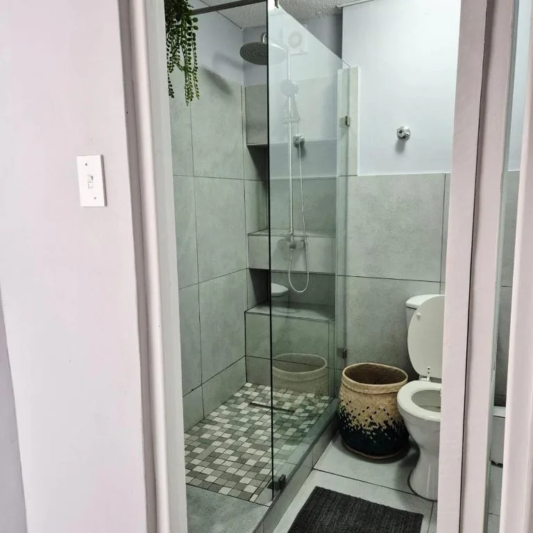 Modern bathroom with large walk-in shower, sage green tiles, white toilet