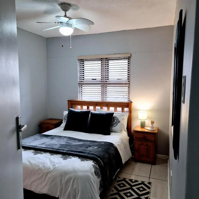 Bedroom with wooden bed frame, white bedding, and ceiling fan overhead