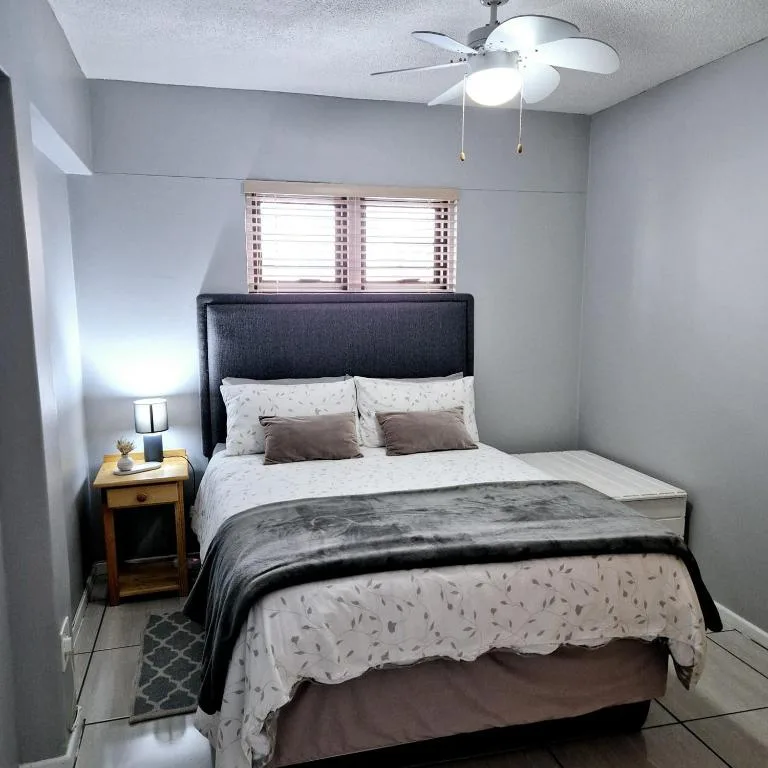 Bedroom with queen bed, dark headboard, wooden nightstand, and ceiling fan