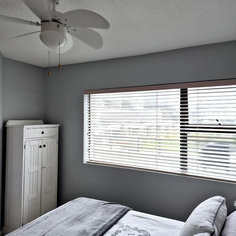 Bedroom with bed, white storage cabinet, and large window with shutters