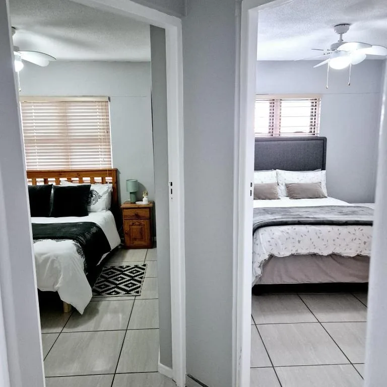 Two neatly made beds in bright, modern bedrooms with neutral furnishings