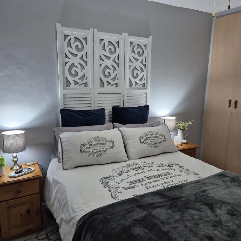 Bedroom with decorative white headboard, patterned pillows, wooden nightstands, and lamps