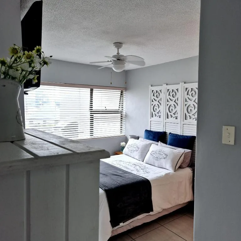 Bright bedroom with double bed, decorative headboard, ceiling fan, and natural light