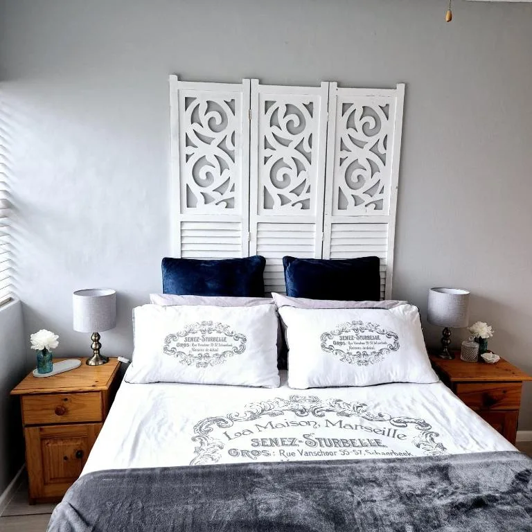 Neatly made bed with white linens, decorative headboard, and navy pillows